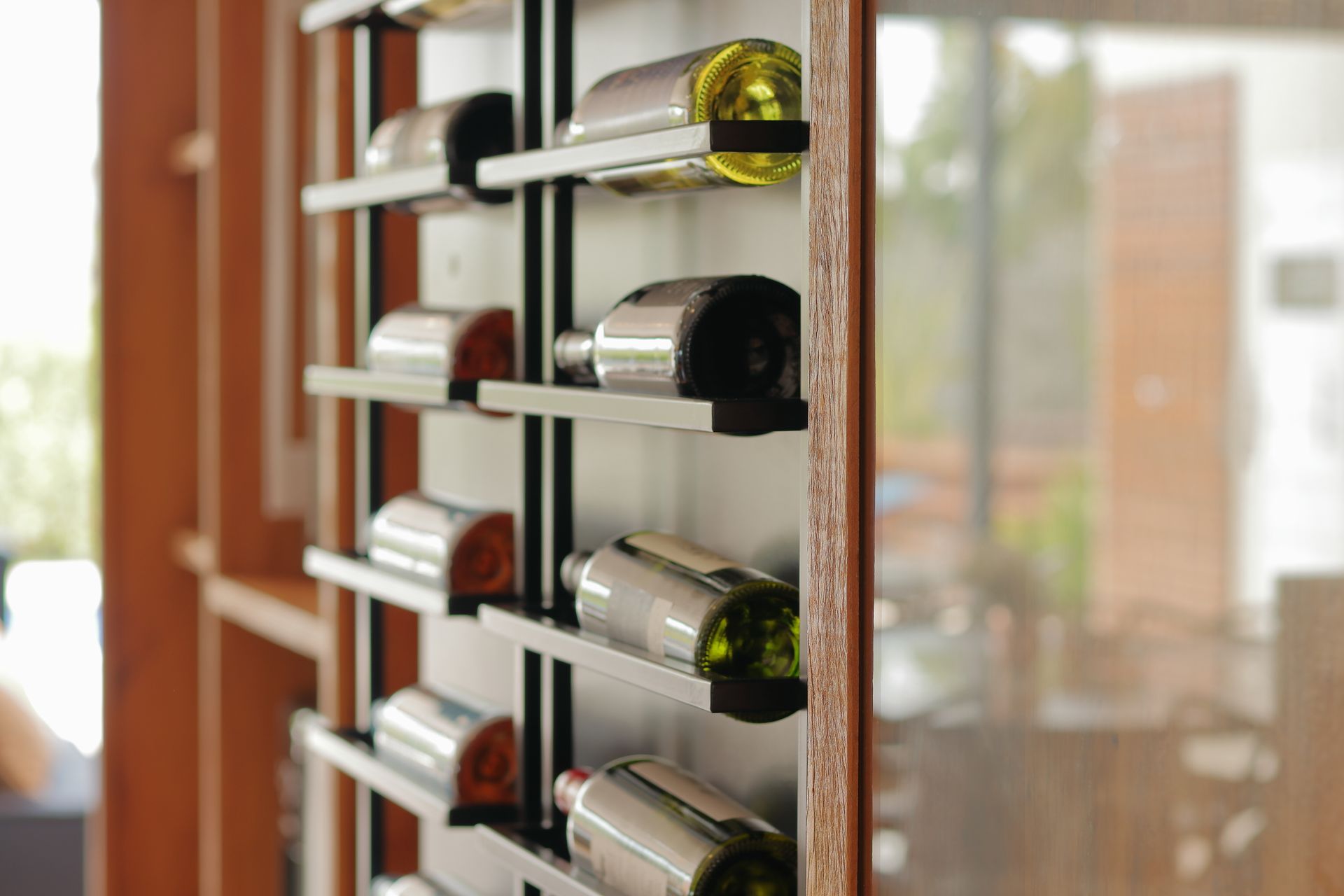 A close-up view of wine bottles on a sleek wooden shelf in natural lighting.
