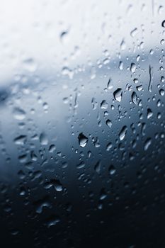 Artistic close-up of water droplets on a glass pane during a rainy day.