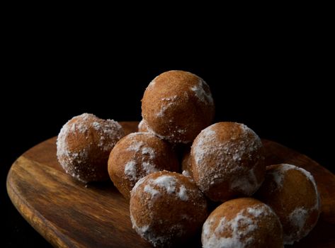 Close-up of sugar-coated donuts on a wooden board, perfect dessert treat.