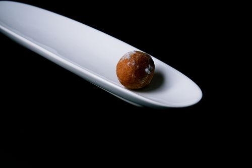 Free Minimalist image of a single sweet praline on a sleek white plate against a black backdrop. Stock Photo