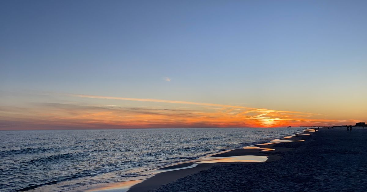 Breathtaking sunset view over the Gulf Shores beach with gentle waves and colorful sky.