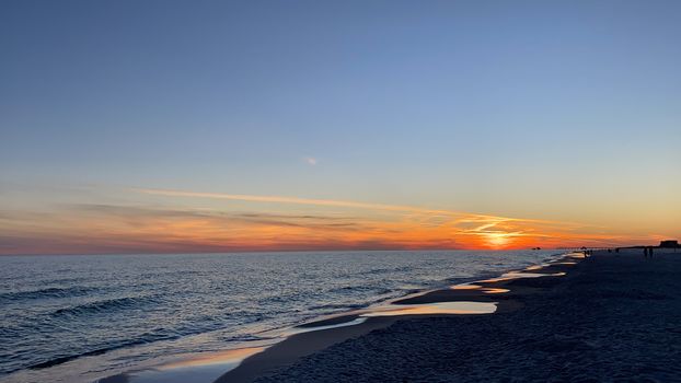 Breathtaking sunset view over the Gulf Shores beach with gentle waves and colorful sky.