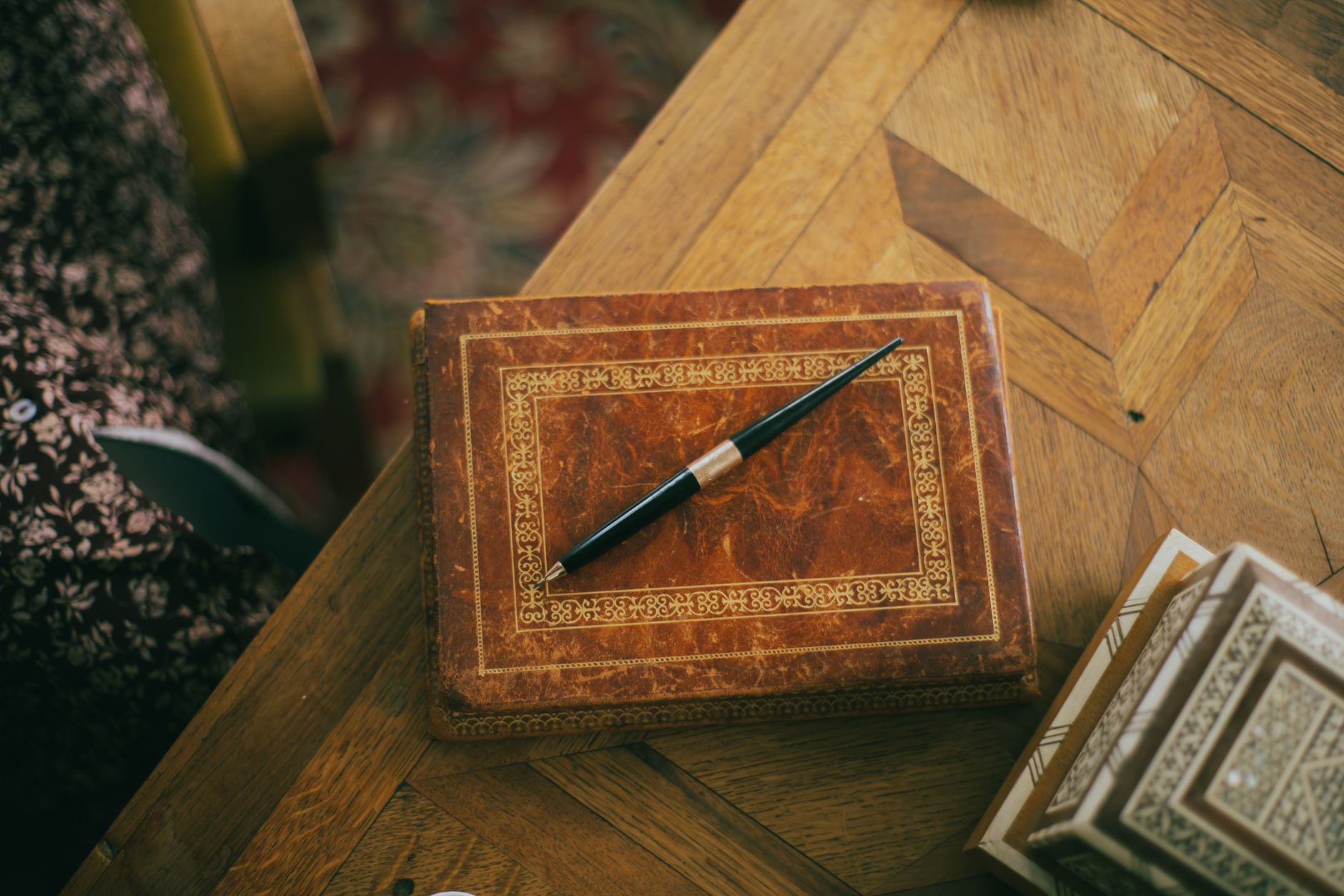 A close-up view of an elegant vintage pen resting on an ornate leather-covered wooden box.
