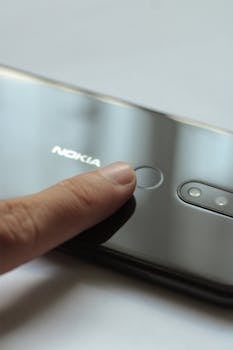 Close-up of a finger touching a smartphone's fingerprint scanner for secure access.