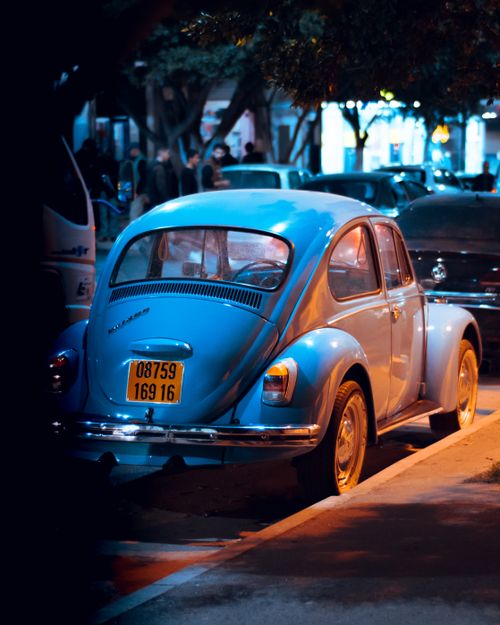 Free Vintage blue Volkswagen Beetle parked at night under streetlights in Algeria. Stock Photo