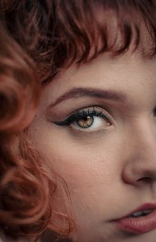 Artistic close-up capturing the eye and expression of a woman with auburn hair.