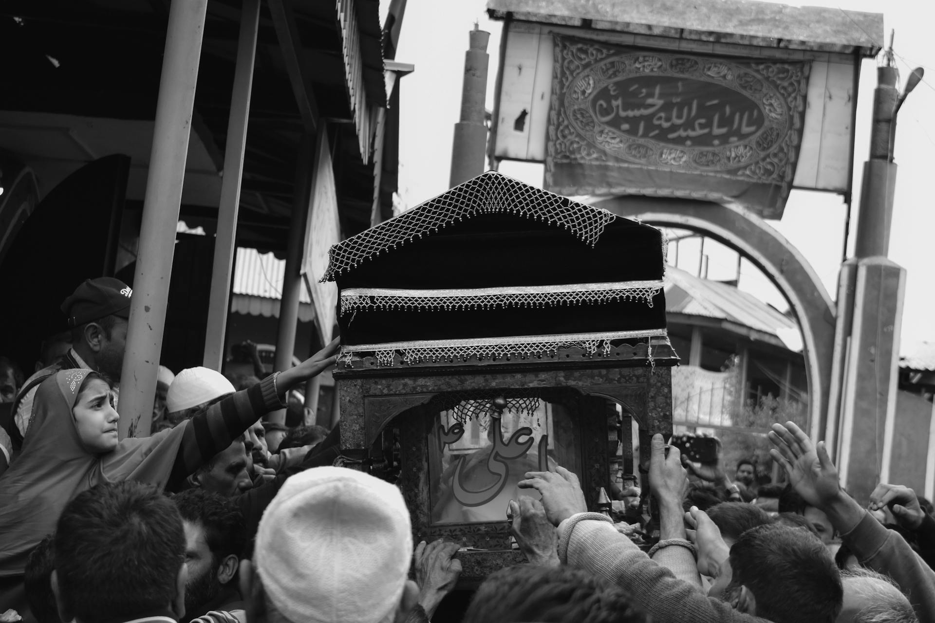 Crowd gathered for a traditional funeral procession in grayscale.