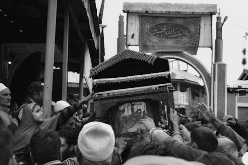 Grayscale Photo of People Reaching a Casket