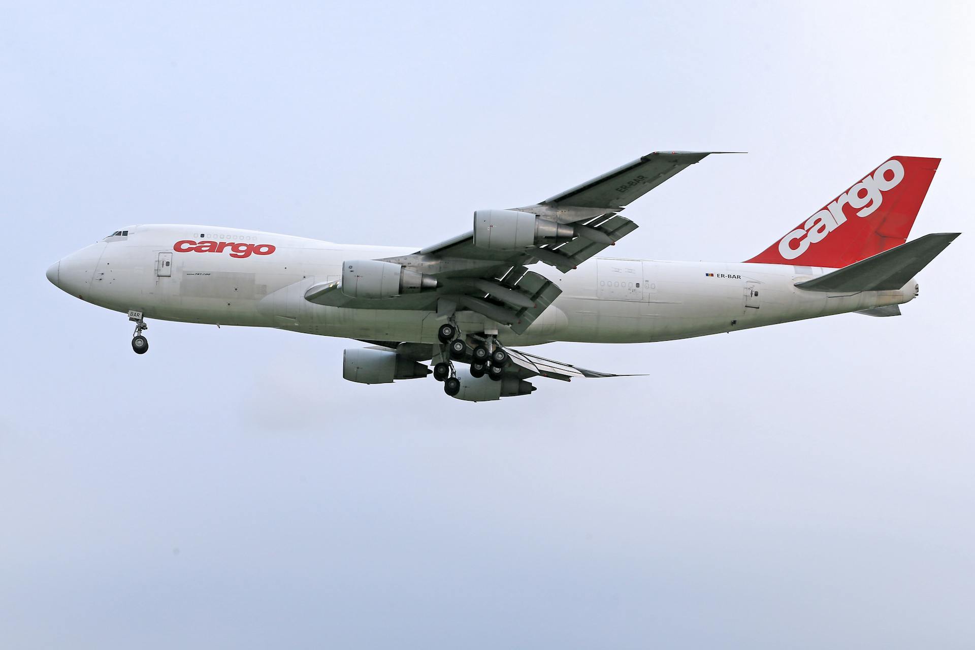 A white cargo airplane in flight against a clear blue sky, showcasing transportation and aviation industry.