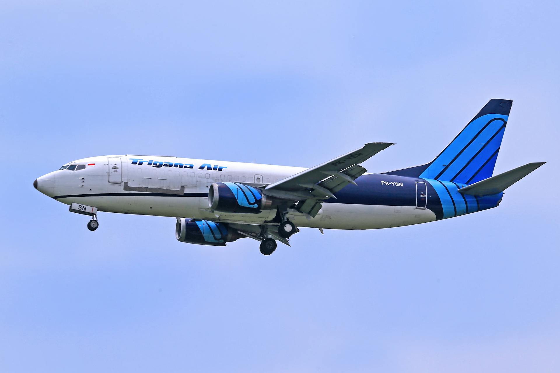 Trigana Air cargo plane flying against a clear blue sky, showcasing aviation in action.