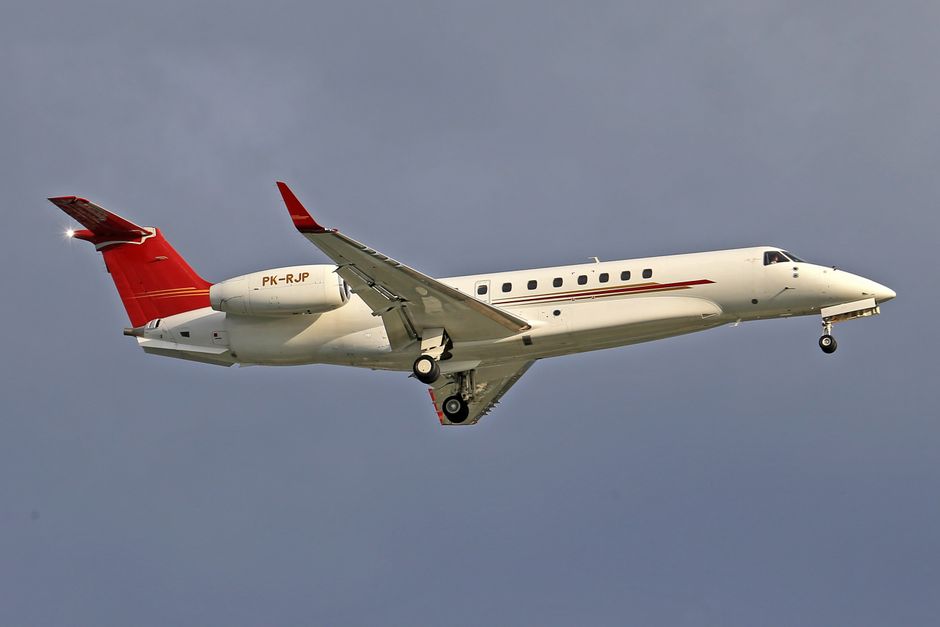 Vista aproximada de um jato particular em voo contra um céu claro, capturando a elegância da aviação.