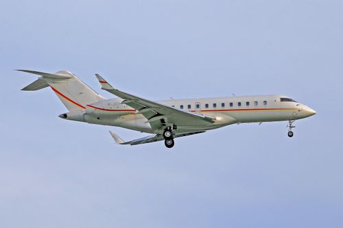 Free A sleek Bombardier Global Express jet in flight against a clear blue sky. Stock Photo