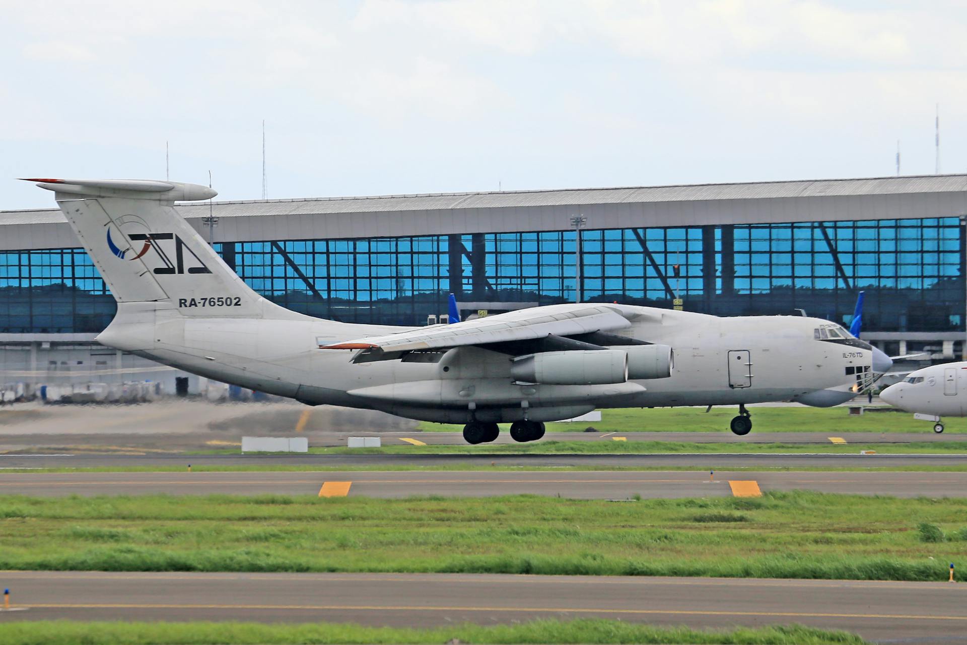A military cargo airplane stationed at an airport runway during the day.