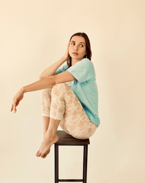 Woman in Blue Shirt Sitting on a Stool