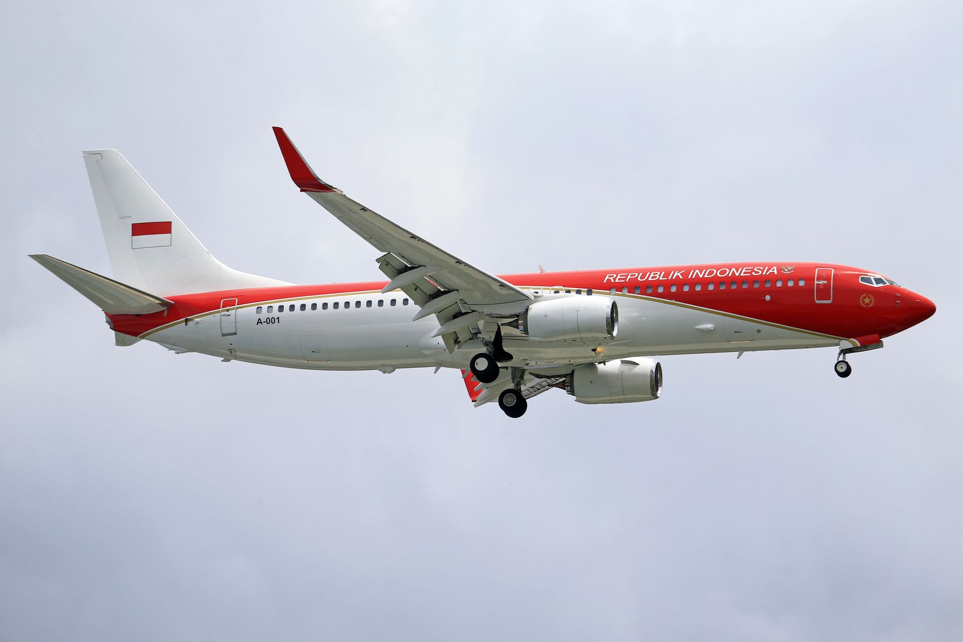 A side view of a Republic Indonesia aircraft flying in a cloudy sky.