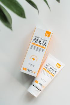 Close-up of sunblock packaging for sensitive skin on a white surface.