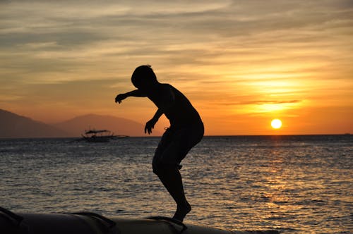 Free Silhouette of Person Standing on Sand during Sunset Stock Photo