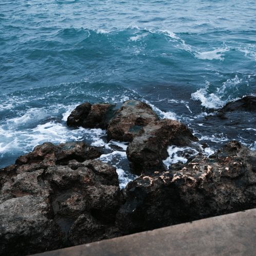 Free A vibrant scene of ocean waves crashing against a rugged rocky coastline, showcasing the power of nature. Stock Photo
