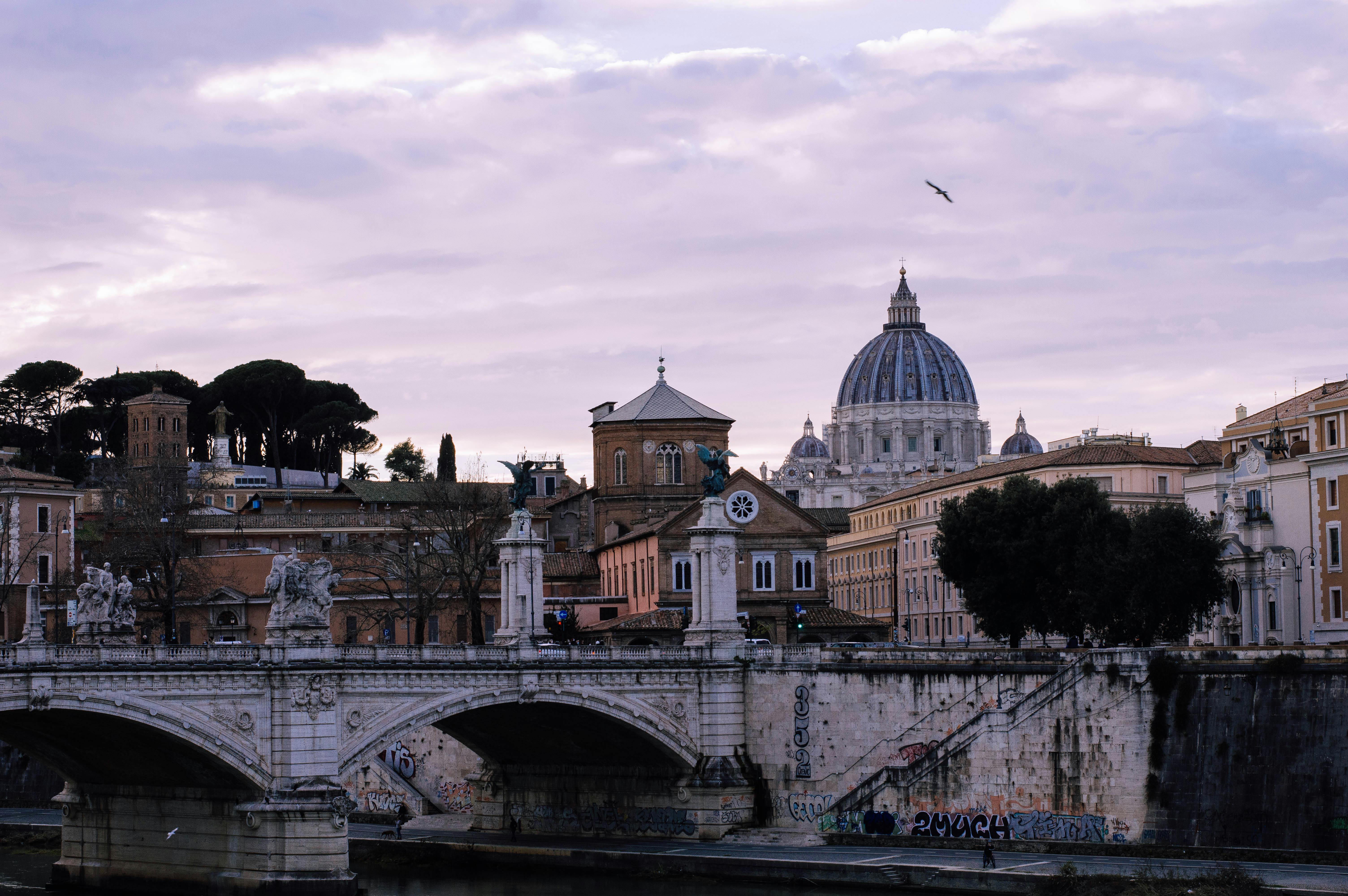 View of the iconic St. Peter's Basilica and bridge over the Tiber River in Rome, Italy.
