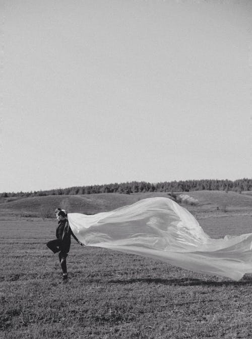 Woman Holding a Veil on a Field 