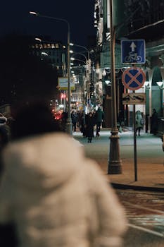 Nighttime street view in Moscow with people walking and city lights.