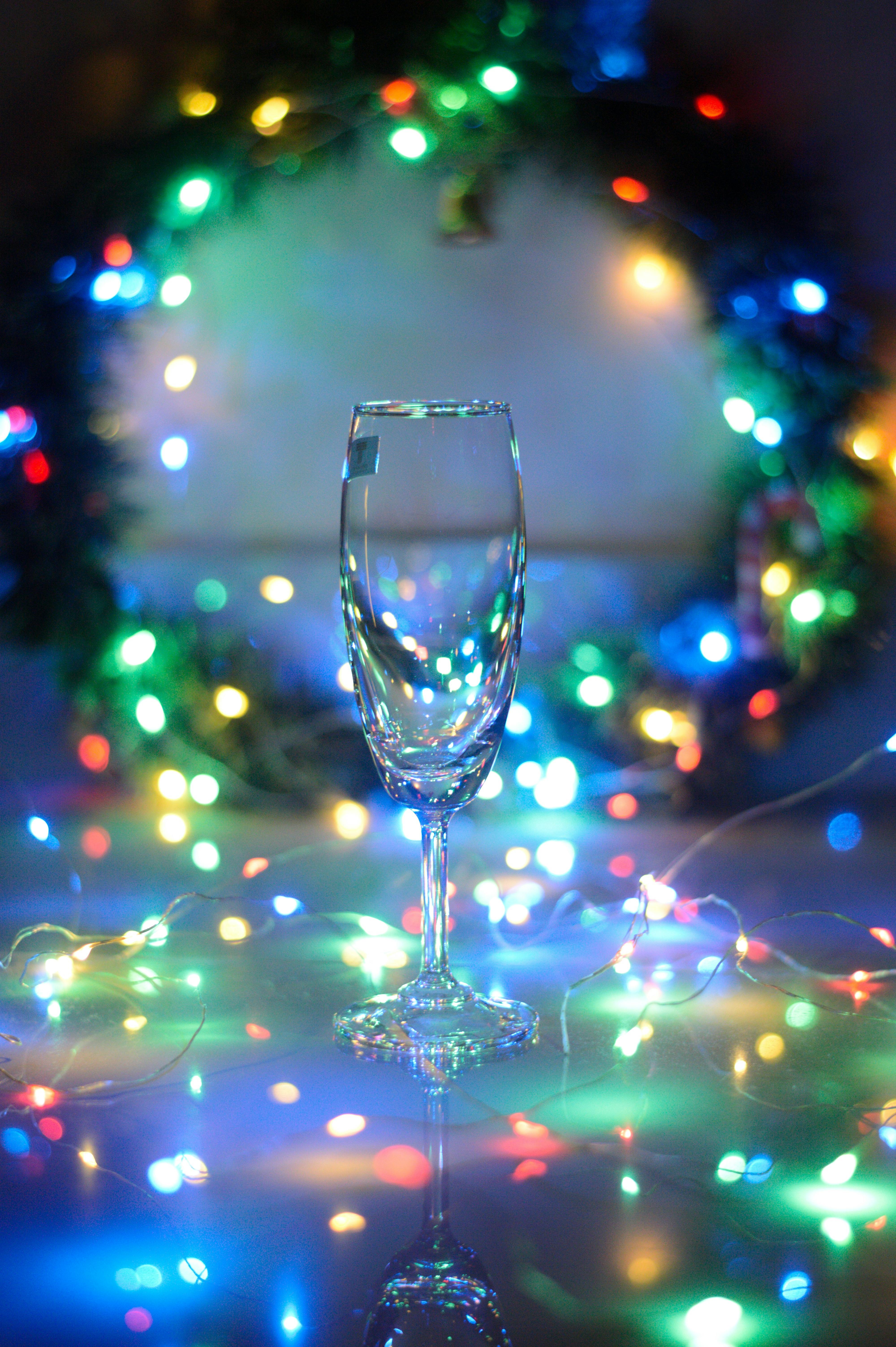 Close-up of a champagne glass with vibrant, colorful Christmas lights in a festive background.