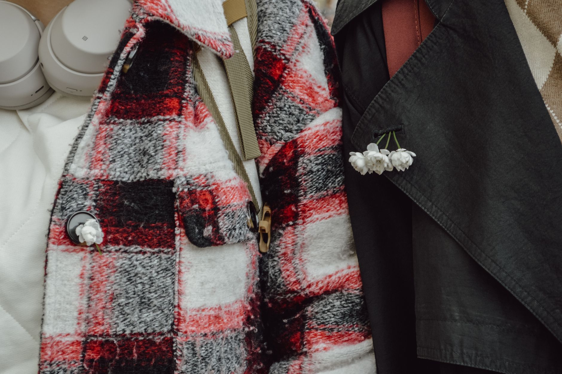 Close-up of a checkered coat with white flowers and headphones, showcasing winter fashion.