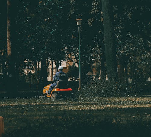 Free Man in Blue Coveralls Riding a Lawn Mower Stock Photo