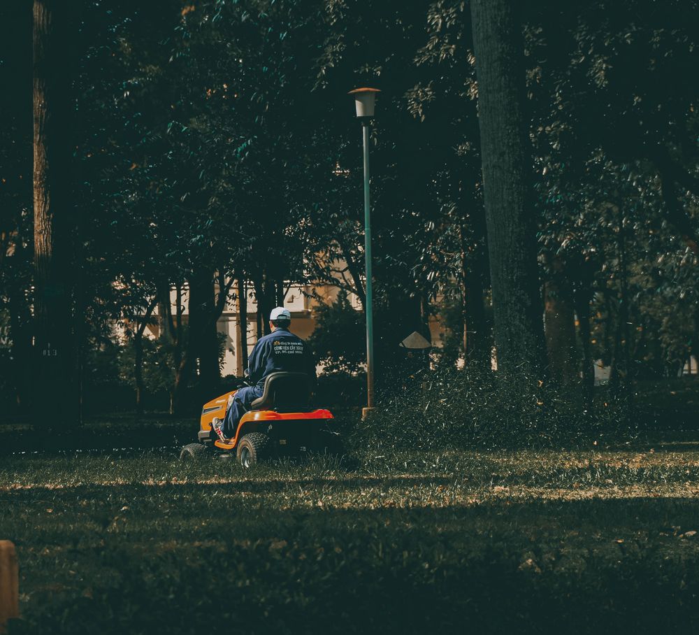 Landscaper riding a mower across a large green lawn