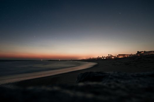 A serene twilight view of Los Angeles beach with a dark sky and city lights.