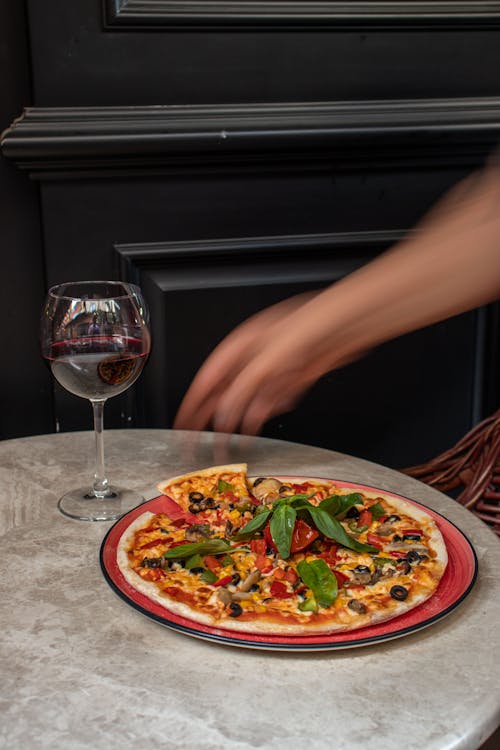 Pizza on a Ceramic Plate Near a Glass of Wine