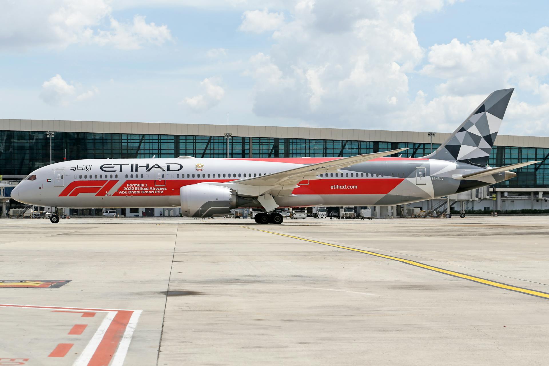 Etihad Airways Boeing 787 with Formula 1 livery parked at a modern airport.