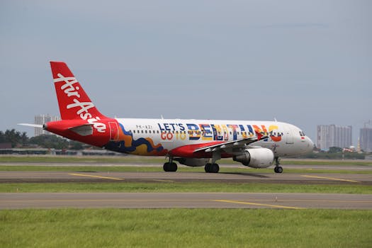 AirAsia Airbus A320 with vibrant livery taxiing on a runway on a cloudy day.