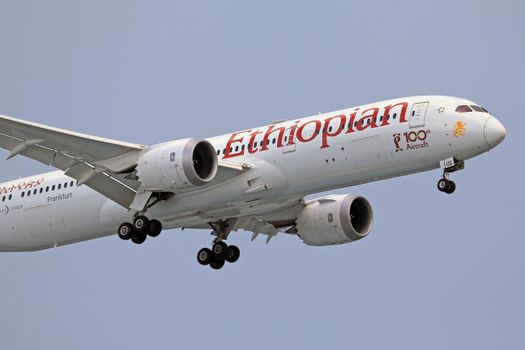 Ethiopian Airlines Boeing 787 aircraft landing with visible gear against a clear sky.