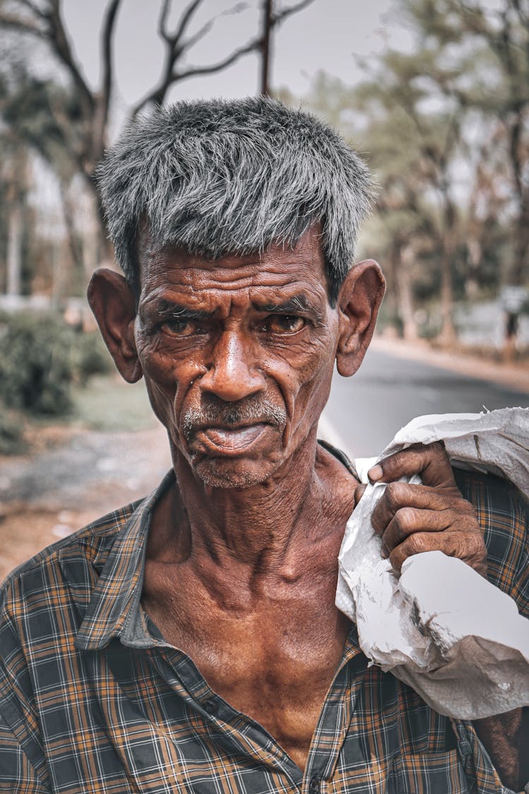 Poor Elderly Man Carrying Load On Street