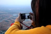 一名妇女用智能手机拍摄印度南迪山的风景