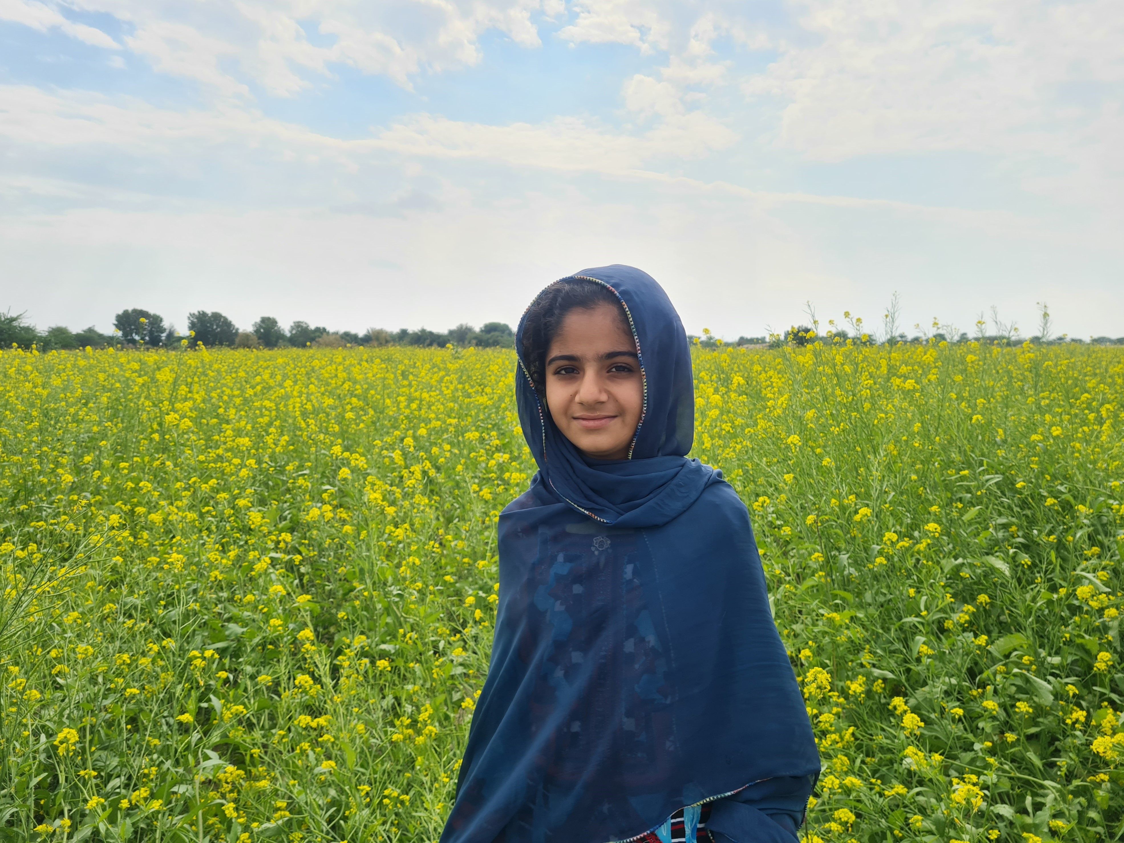 A young girl in a hijab standing in a vibrant flower field, embodying cultural tradition and natural beauty.