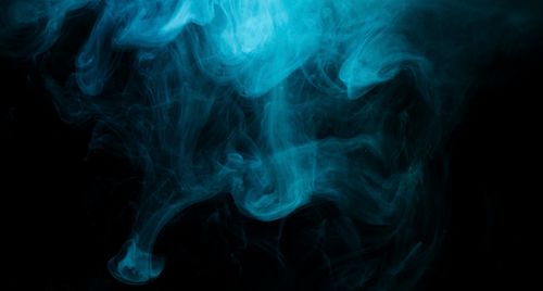 Free Dynamic blue smoke swirling against a dark background, creating a mysterious and abstract effect. Stock Photo