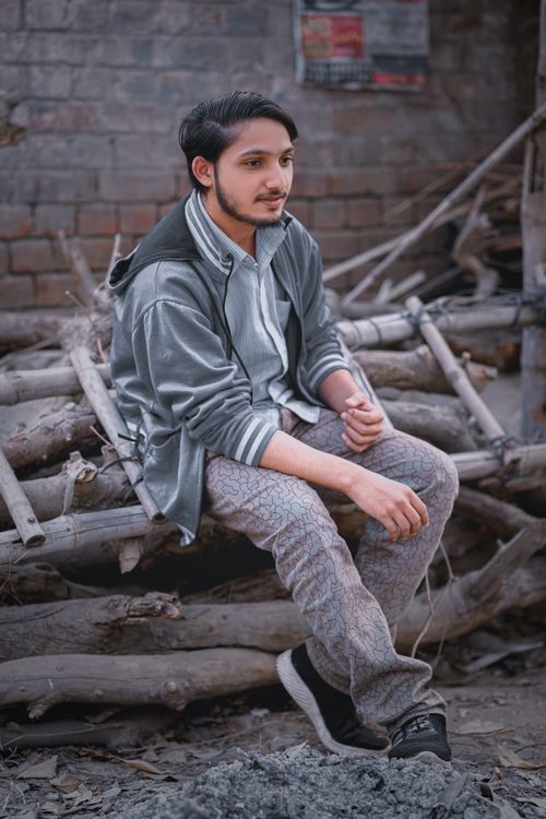 Free Casual portrait of a young man sitting on logs in an urban setting in Lahore, Pakistan. Stock Photo