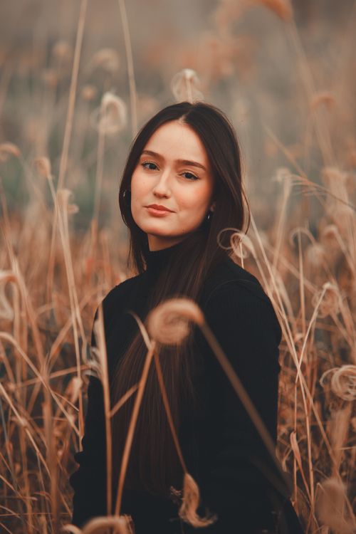 Free A serene portrait of a woman standing in a field, surrounded by dried flora. Stock Photo