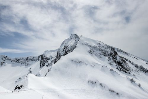 Free Majestic snow-covered mountain peak beneath a cloudy sky, ideal for winter scenery. Stock Photo