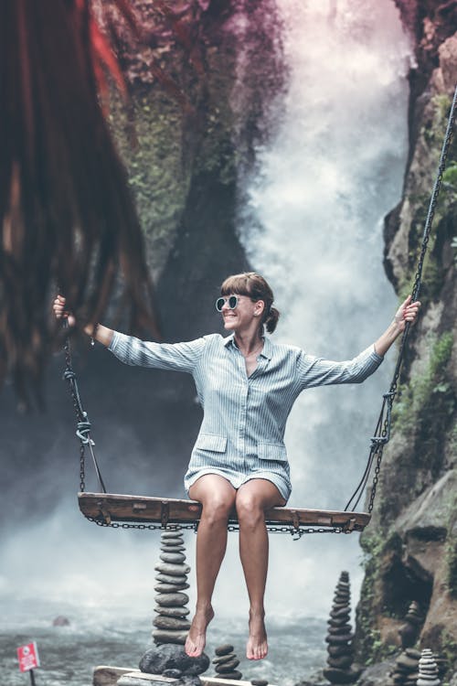Free Woman Sitting on Swing Chair With Waterfalls Background Stock Photo