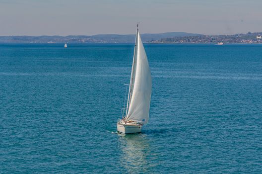 Sailboat cruising on Lake Constance, Friedrichshafen under clear blue skies.