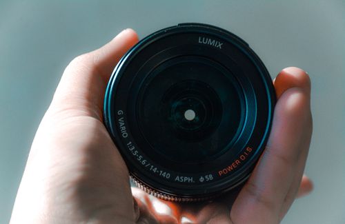 Free A close-up view of a hand holding a LUMIX camera lens, showcasing its details. Stock Photo