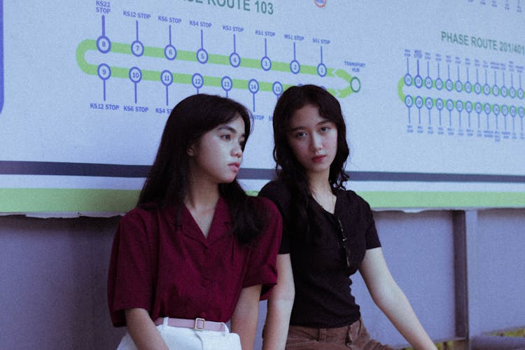 Women Sitting On Bench Under Metro Sign