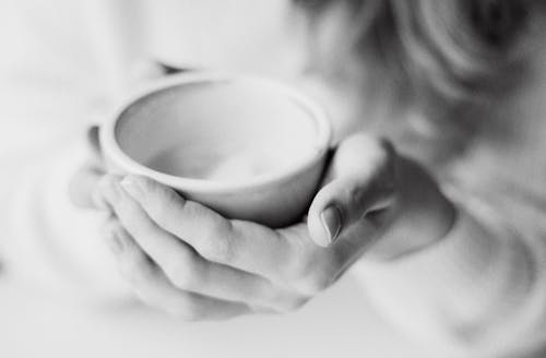 A Grayscale Photo of a Person Holding a Cup