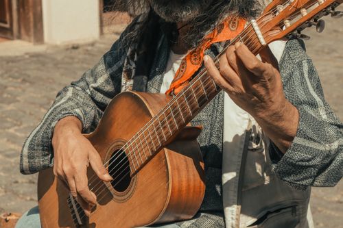 Free Close-up of a street musician playing an acoustic guitar outdoors, showcasing intricate fingerwork. Stock Photo