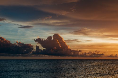 Free A stunning sunset over the ocean with dramatic clouds and reflections. Stock Photo