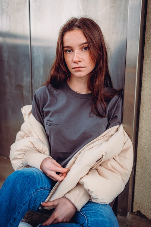 A Woman in Gray Shirt Leaning on a Metal Surface