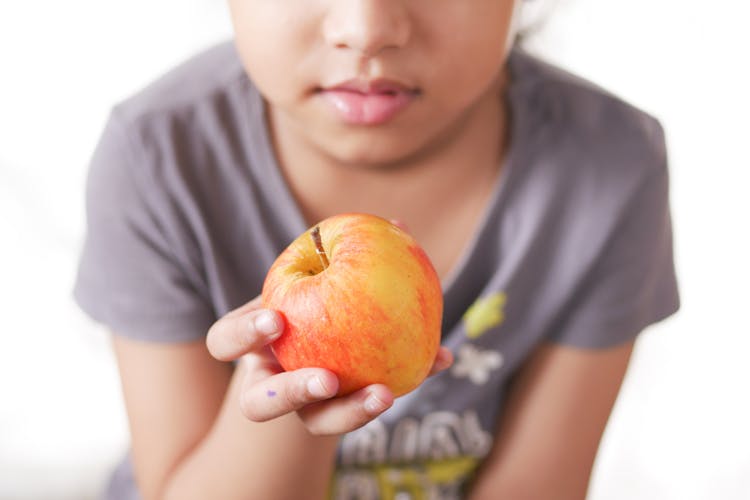 Close Up Photo Of Kid Holding An Apple